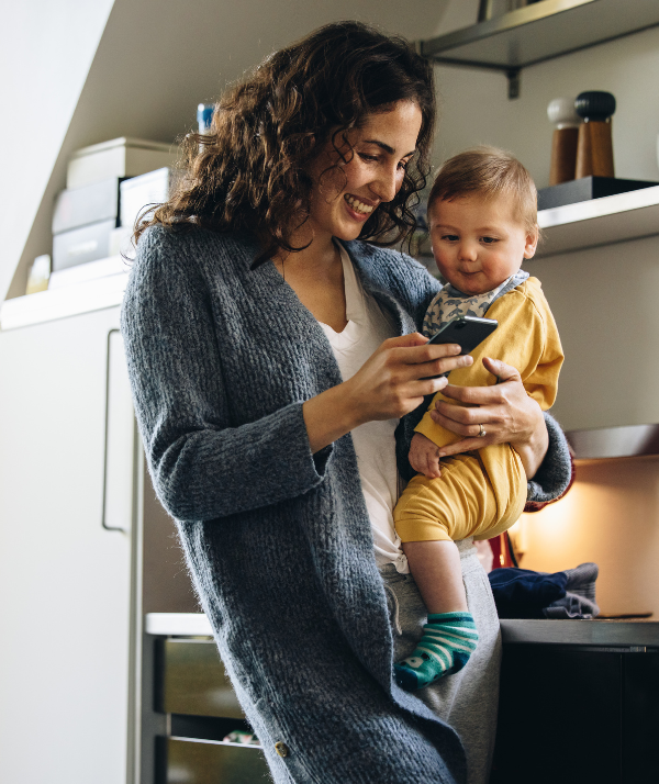 Mother holding child while using her smartphone